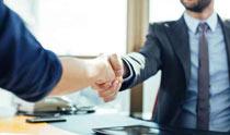 Two people shaking hands over a table.