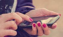 A person with pink nails is holding a cell phone.