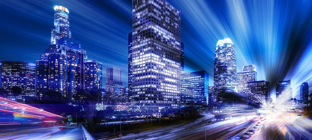 A city skyline with buildings lit up at night.